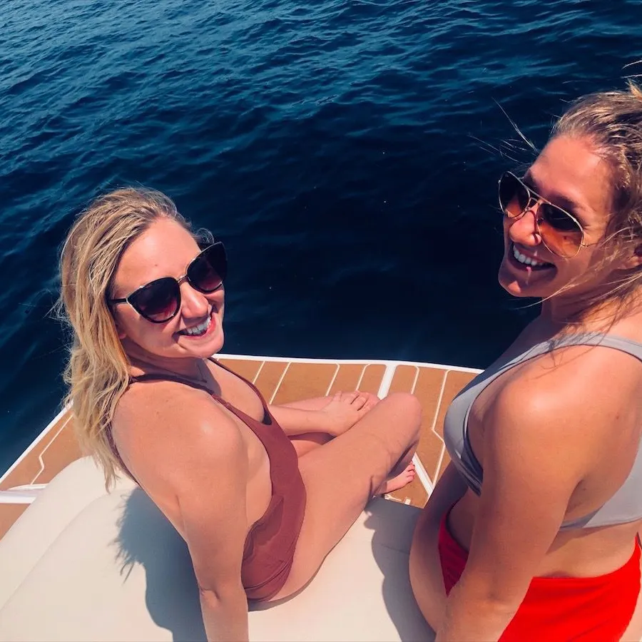 a woman sitting next to a body of water